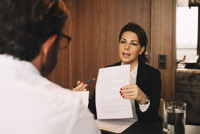 Confident lawyer discussing over document with male client at law office