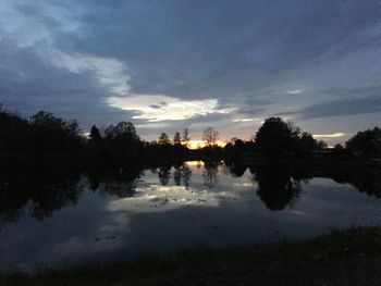 Reflection of silhouette trees in lake against sky