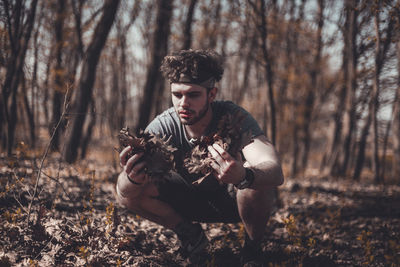 Young man holding camera in forest