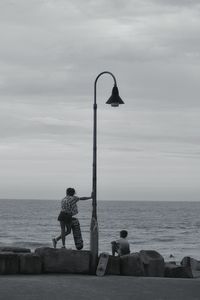 People sitting by sea against sky