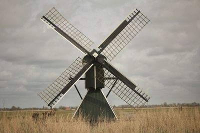 Traditional windmill on field against sky