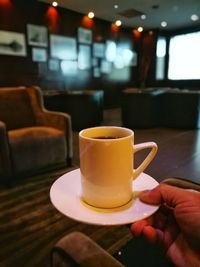 Close-up of hand holding coffee cup on table