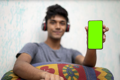 Portrait of young man sitting on bed at home