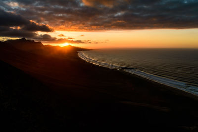 Scenic view of mountains by sea against sky during sunset