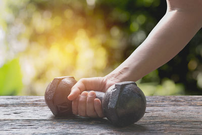 Cropped hand of man lifting dumbbell on table