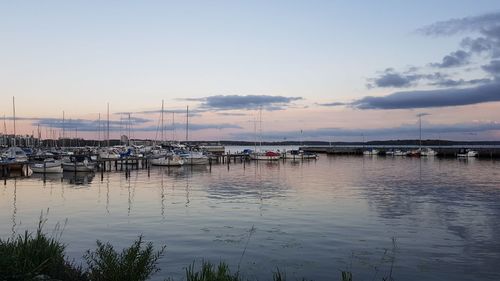 Boats moored in harbor at sunset