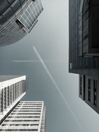 Directly below shot of buildings against vapor trails in clear sky