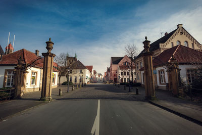 Empty street amidst houses against sky