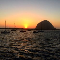 Silhouette boats sailing in sea against clear sky during sunset