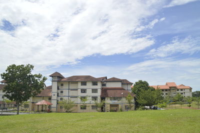 Houses on field by lawn against sky