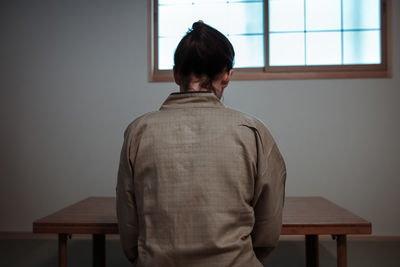 Rear view of man standing against window