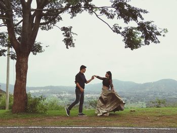 Couple holding hands and dancing against landscape 