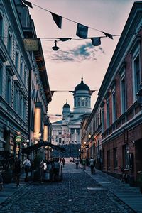 People on street amidst buildings against sky in city