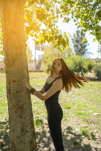 Young woman standing against tree