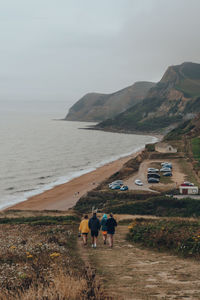 Rear view of people walking on beach against sky