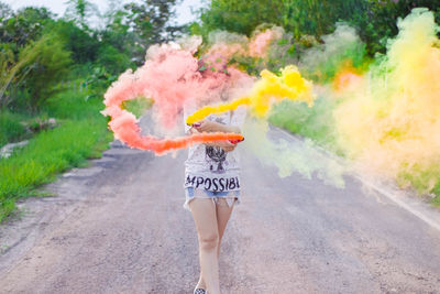 Woman holding smoke bombs on road