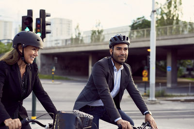 Smiling business colleagues cycling in city