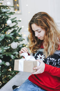 Young woman holding christmas tree in box