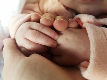 Cropped image of mother and baby holding hands