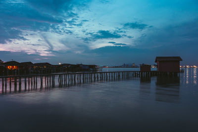 Scenic view of lake by buildings against sky at dusk