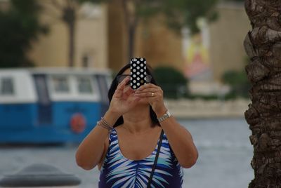 Woman photographing through mobile phone in city