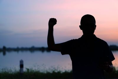 Rear view of silhouette man standing against sky during sunset