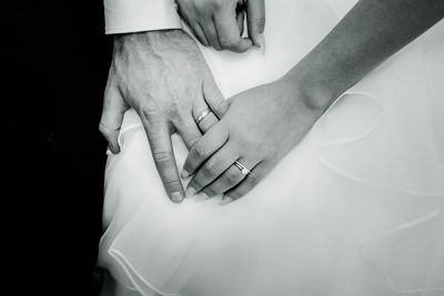 Midsection of bride and bridegroom holding hands during wedding ceremony