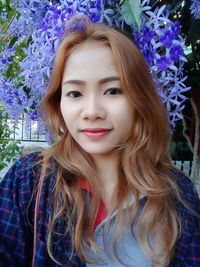 Portrait of smiling young woman against flowering plant