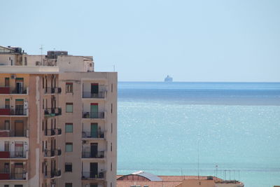 Buildings by sea against clear sky