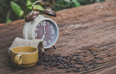 A brown alarm clock and coffee beans in a sack bag, on old wood table, selective focus