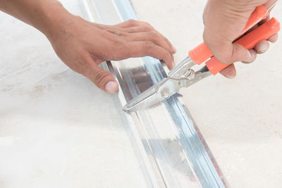 Cropped hands of man working with plier on metal