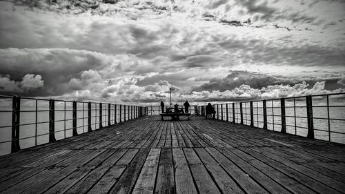 People on pier against sky
