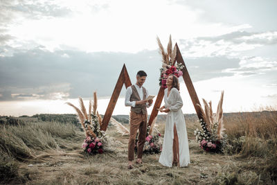 People on field by traditional windmill against sky