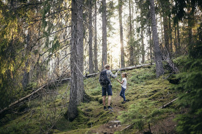 Father with backpack talking to daughter in forest