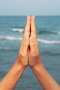 Cropped image of hands clasped against sea