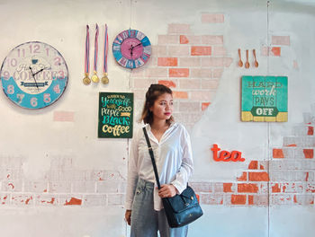 Portrait of female friends standing against wall