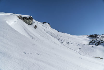Scenic view of snow covered mountains against clear blue sky