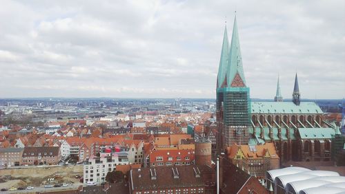 View of cityscape against cloudy sky