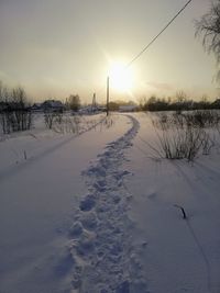 Snow covered field against sky during sunset