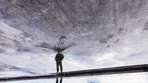 Low section of man standing by damaged umbrella on wet street