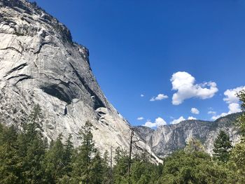 Low angle view of rocky mountains against blue sky