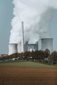 Smoke emitting from factory against sky