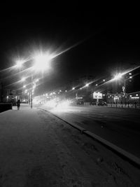 Illuminated street lights on road in city at night