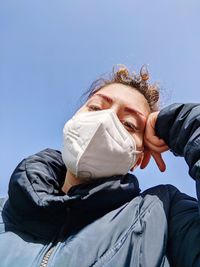 Low angle portrait of woman against blue sky