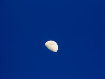 Low angle view of half moon against clear blue sky