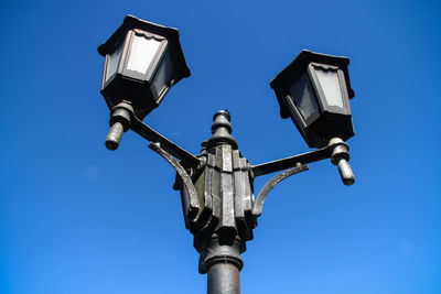 Low angle view of vintage street light against blue sky