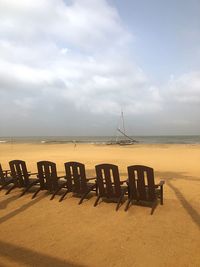 Chairs on beach against sky