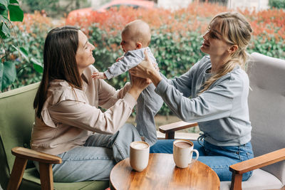 Mother and baby meet a friend, two women communicate, have fun and take care of the child.