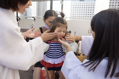 Women applying sunscreen on girl's face