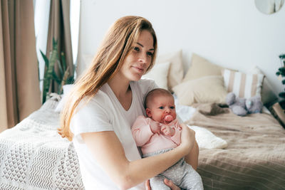 Portrait of cute baby girl lying on bed at home